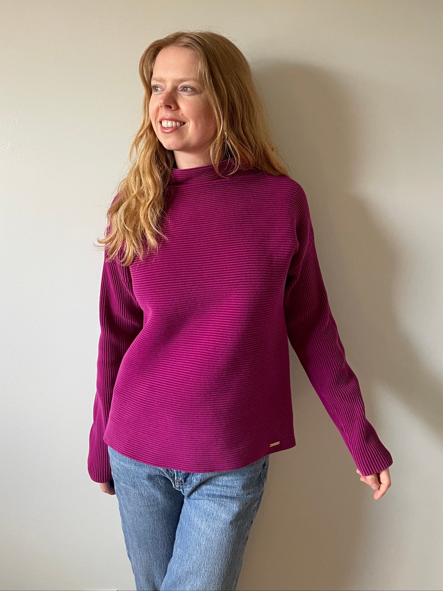 Person wearing a purple sweater and blue jeans on a plain background