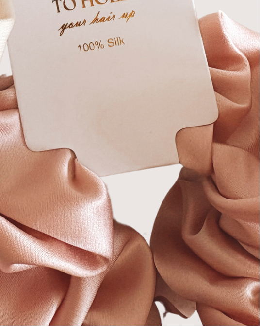 Silky hair ties with branded tags on a light background
