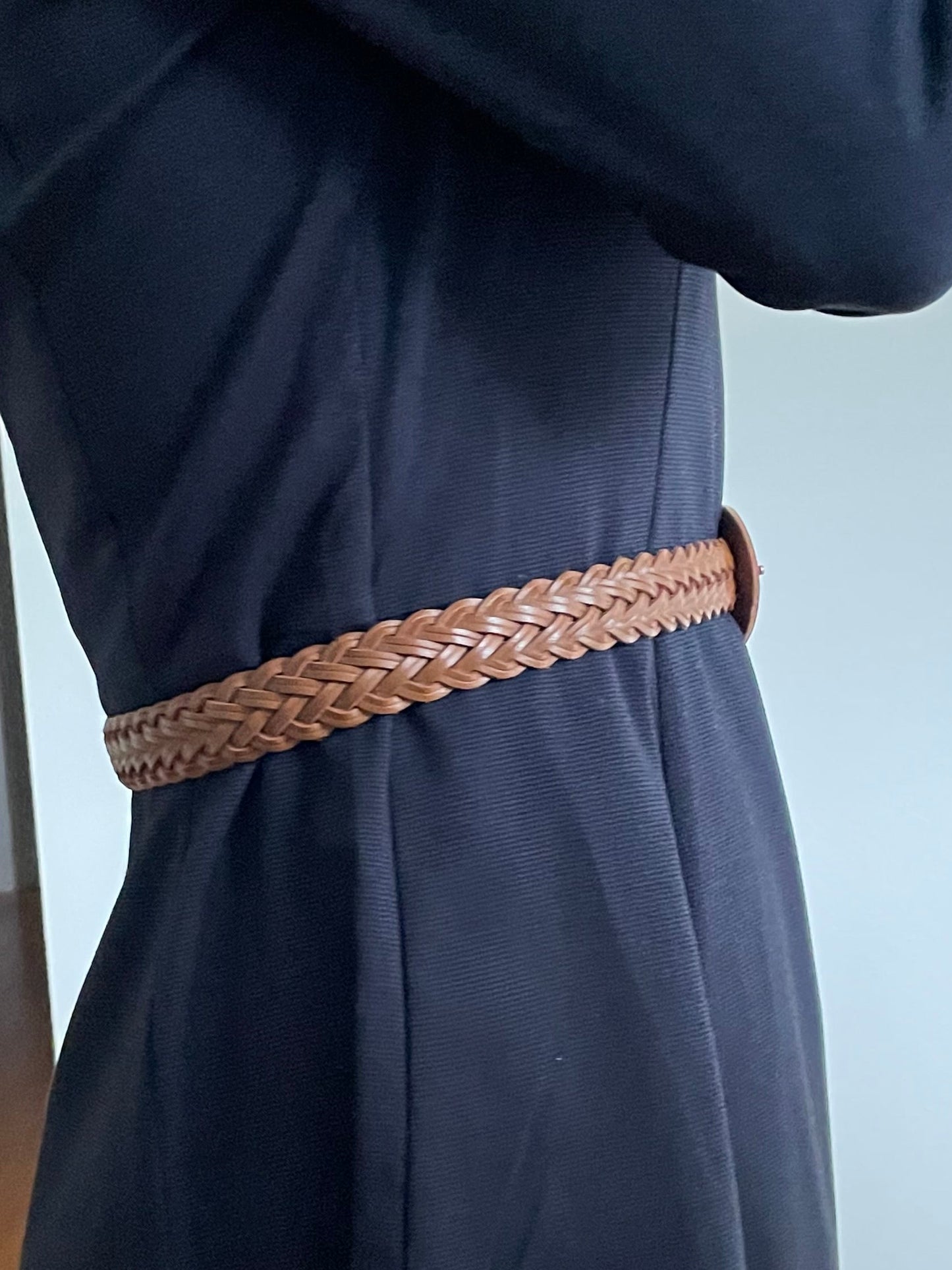 Navy blue pants with a brown belt being worn indoors.