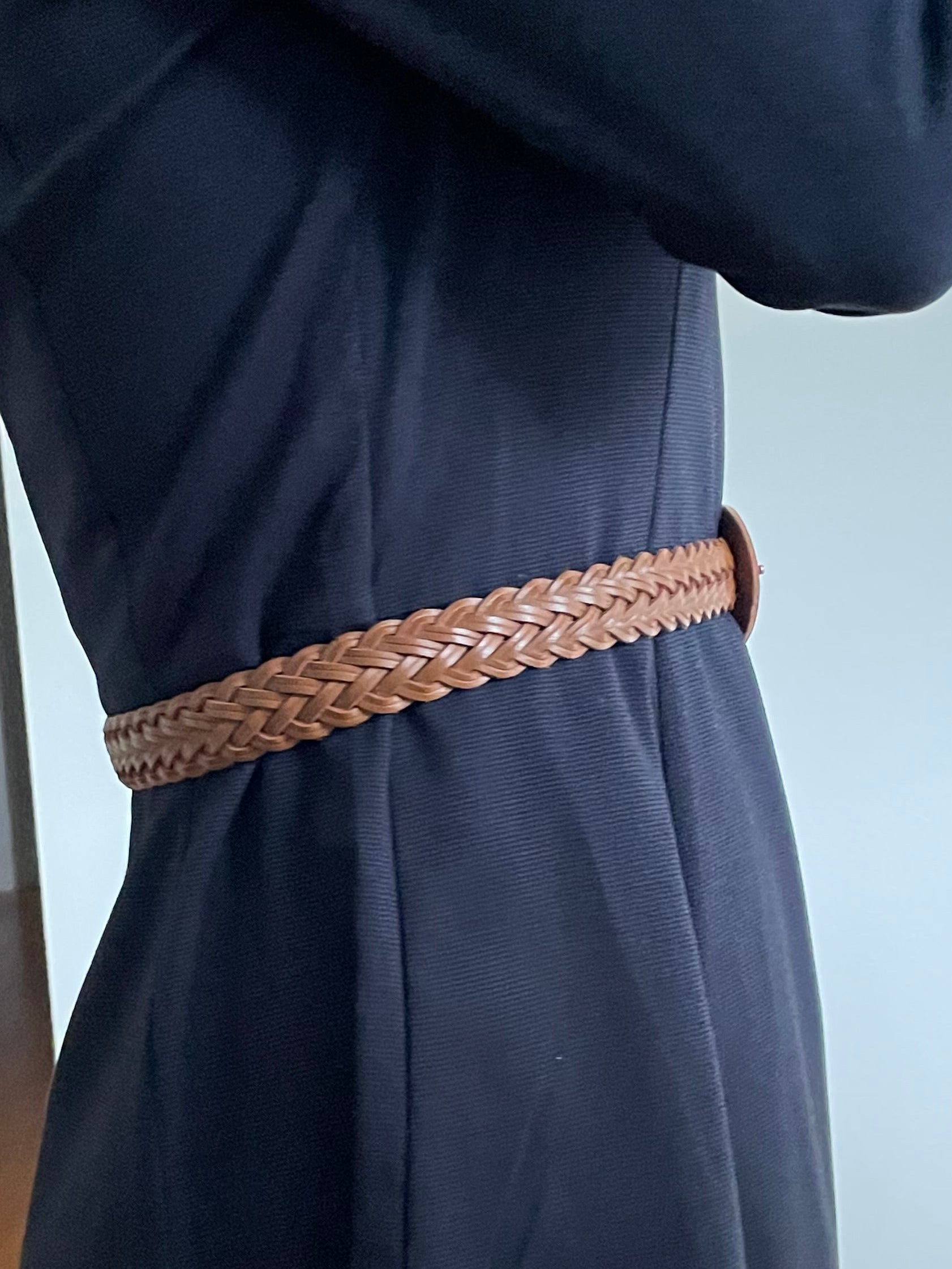 Navy blue pants with a brown belt being worn indoors.