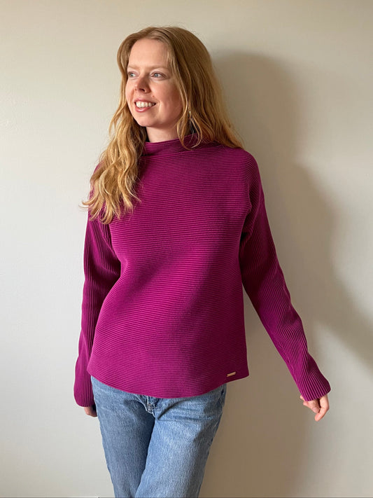 Person wearing a purple sweater and blue jeans on a plain background