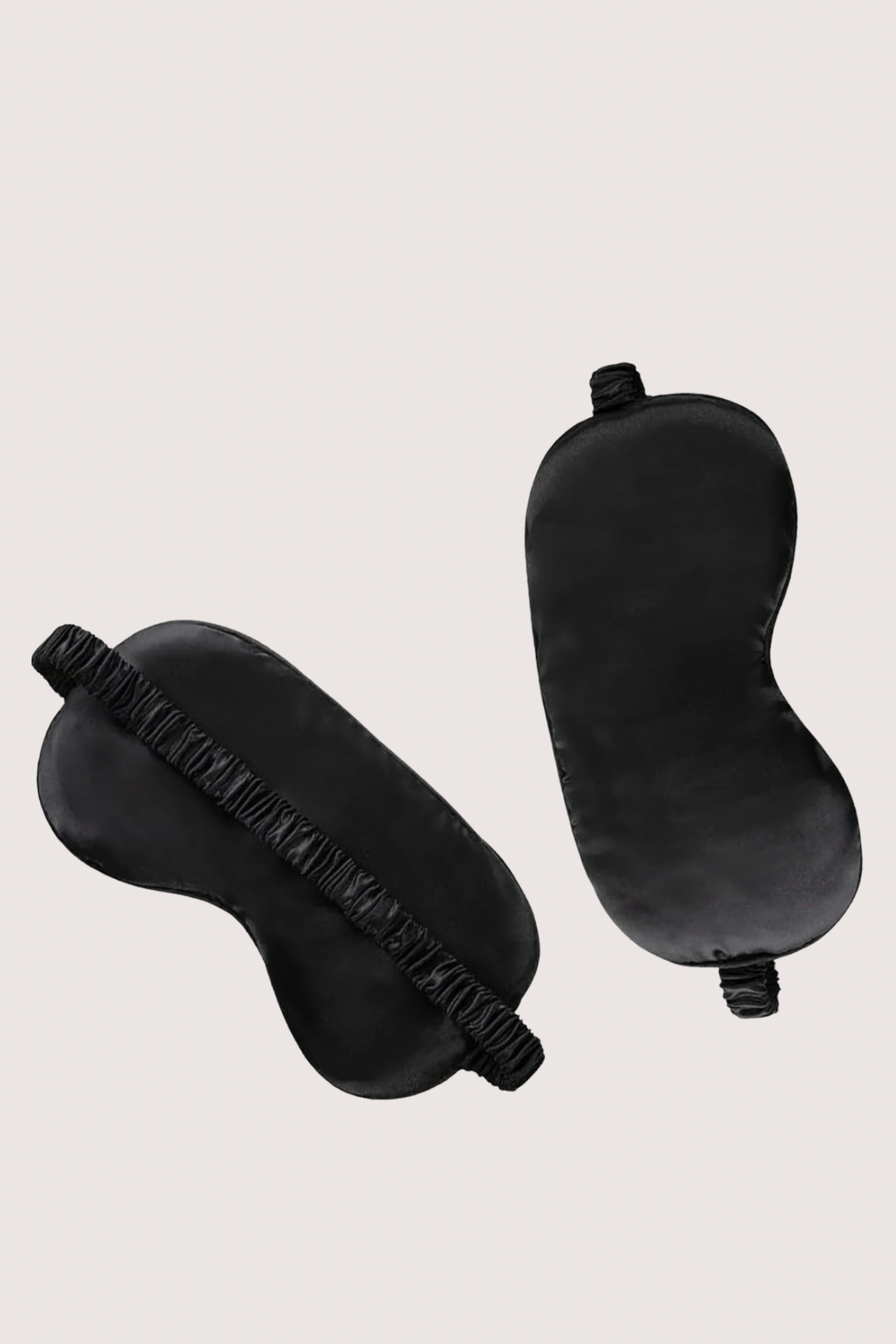 Two black sleep masks on a light beige background